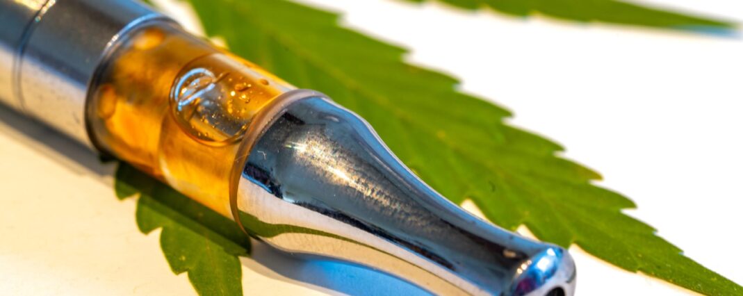 Close up of a CBD vape on a cannabis leaf.