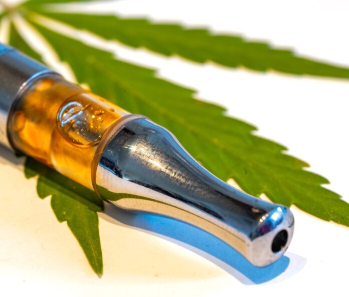 Close up of a CBD vape on a cannabis leaf.